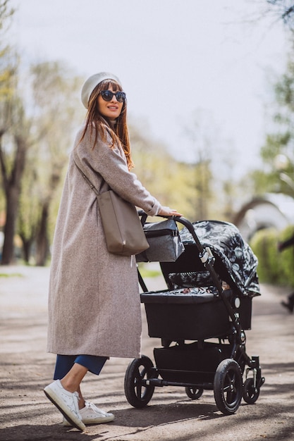 Young mother sitting with baby carriage in park