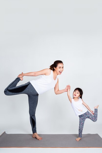 Young mother training lovely daughter with gymnastic