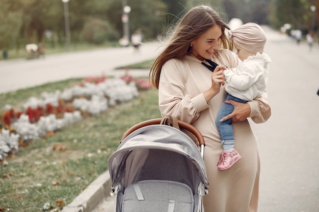 Young mother walking in a autumn park with carriage