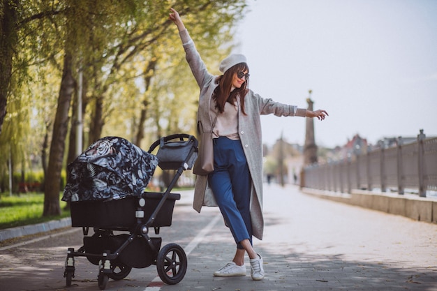 Young mother walking with baby carriage in park