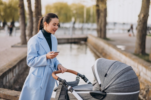 Young mother walking with baby carriage in park