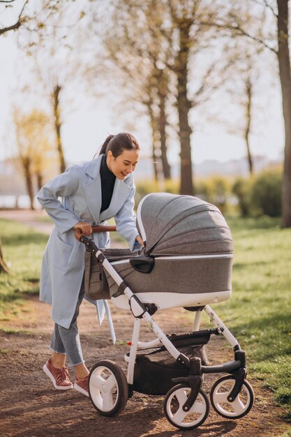 Young mother walking with baby carriage in park