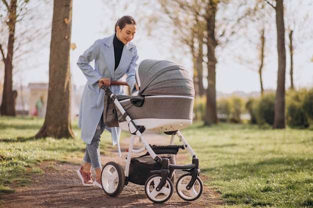 Young mother walking with baby carriage in park