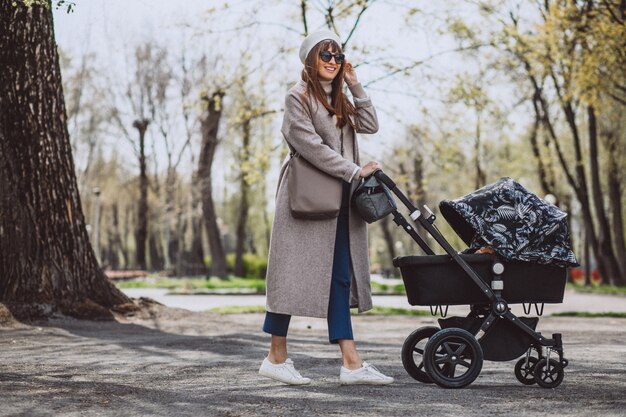 Young mother walking with baby carriage in park