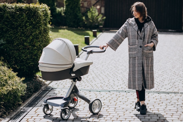 Young mother walking with baby carriage in park