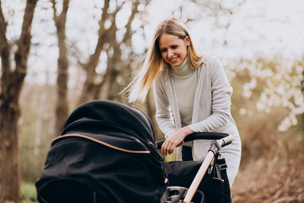 Free photo young mother walking with baby carriage in park