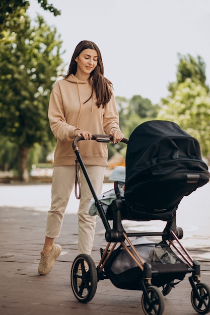 Young mother walking with baby carriage in park