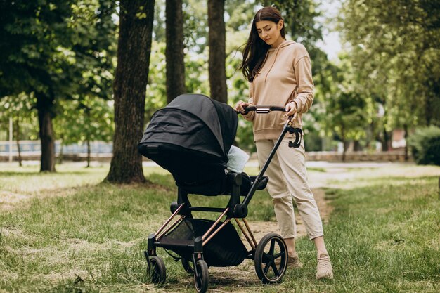 Young mother walking with baby carriage in park