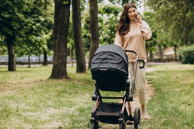 Free photo young mother walking with baby carriage in park