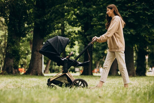 Young mother walking with baby carriage in park