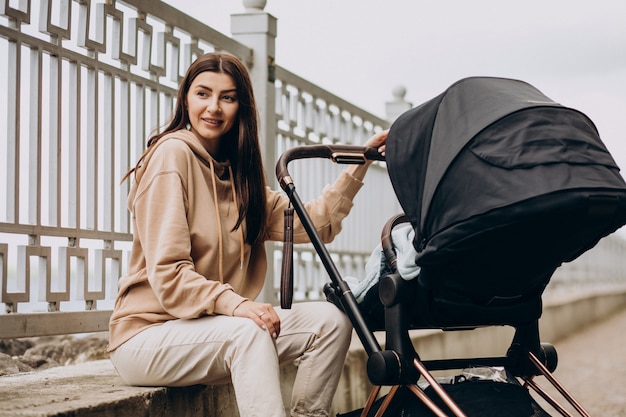 Young mother walking with baby carriage in park