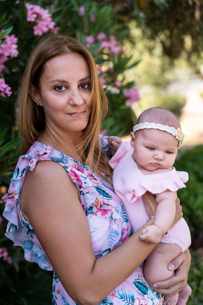 Young mother with a dress with flowers holding her small baby girl