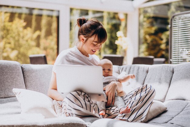 Young mother with her kid working at home on a computer