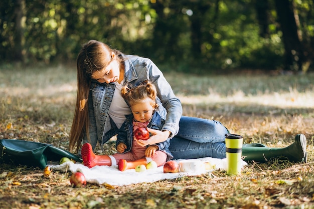 Young mother with her little daughter in an autumn park having picnic