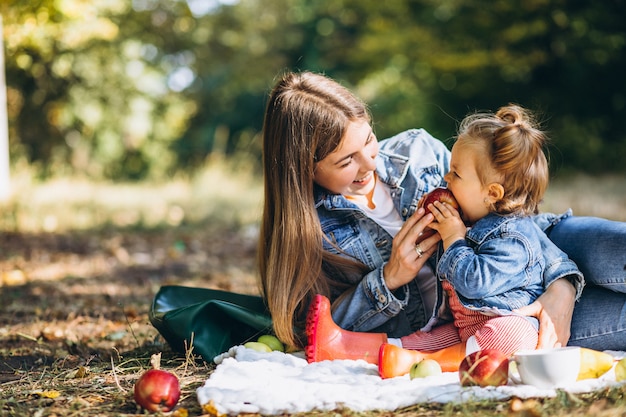 Young mother with her little daughter in an autumn park having picnic