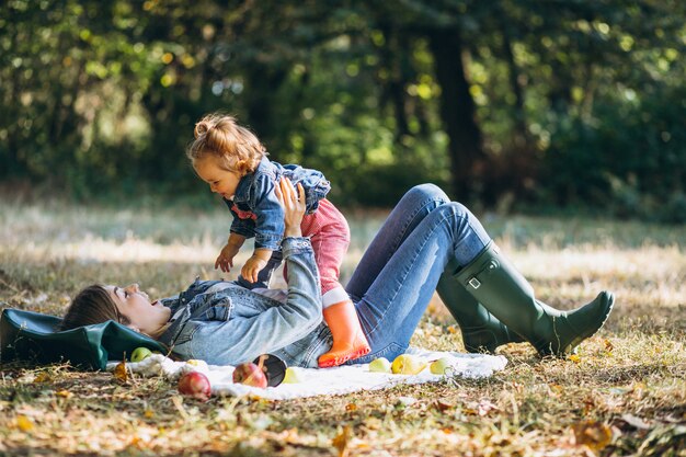 Young mother with her little daughter in an autumn park having picnic