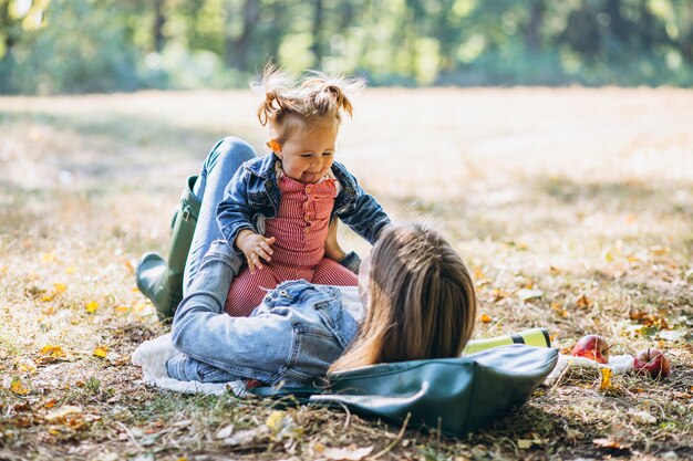 Young mother with her little daughter in an autumn park having picnic