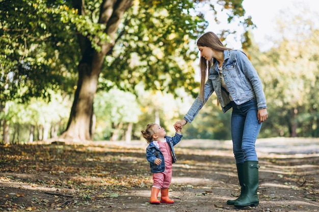 Young mother with her little daughter in an autumn park