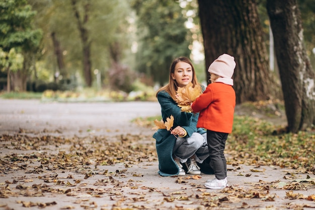 Young mother with her little daughter in an autumn park