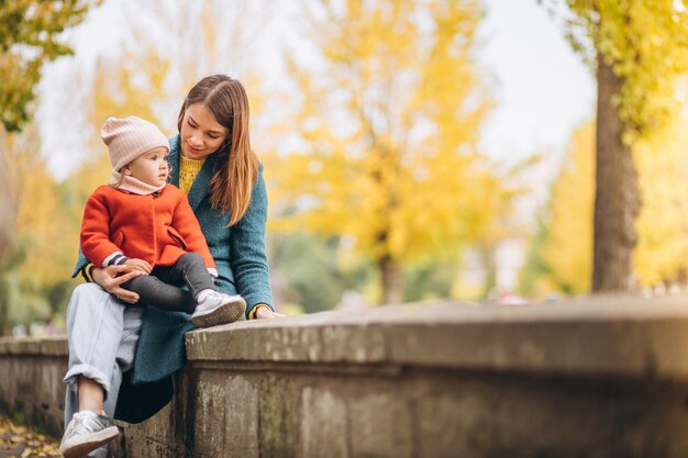 Young mother with her little daughter in an autumn park