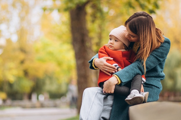 Young mother with her little daughter in an autumn park