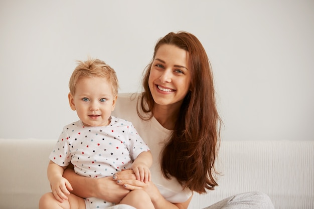 Young mother with her one years old little son dressed in pajamas are relaxing