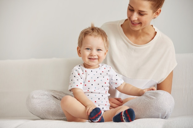 Young mother with her one years old little son dressed in pajamas are relaxing