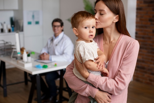 Free photo young mother with her toddler at the pediatrician for a physical examination