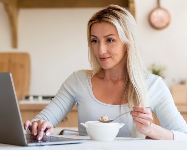 Free photo young mother working and having breakfast at home