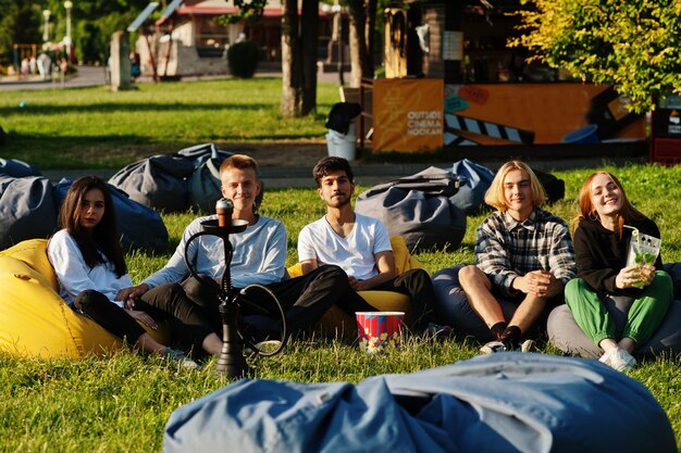 Young multi ethnic group of people watching movie at poof in open air cinema