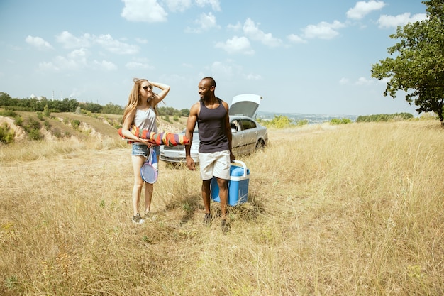 Free photo young multiethnic international romantic couple outdoors at the meadow in sunny summer day. african-american man and caucasian woman having picnic together. concept of relationship, summertime.