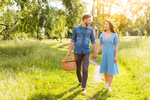 Young multiracial enamored couple walking in park holding hands