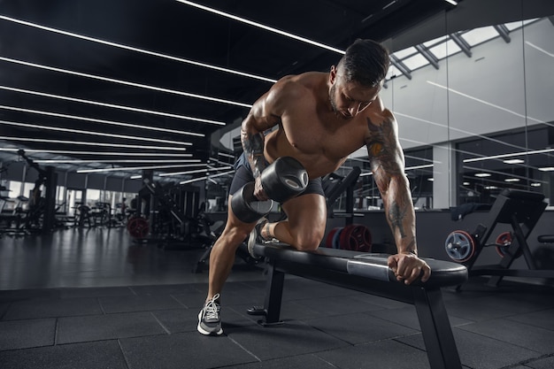 Free Photo young muscular athlete practicing in gym with the weights