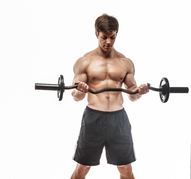 Young muscular guy in black shorts doing exercises with barbell. Isolated on white