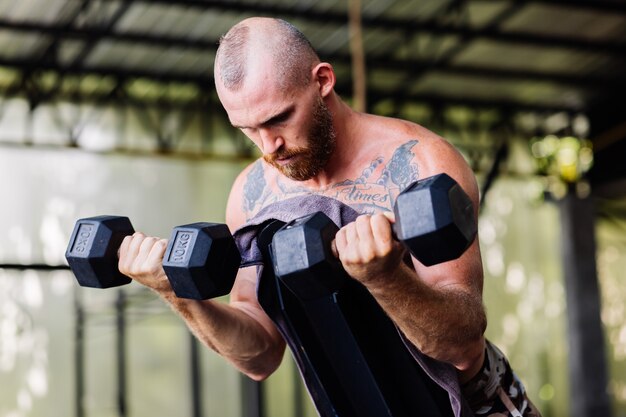 Young muscular tattooed strong muscle bearded european man doing hard exercise