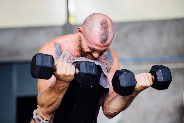 Free Photo young muscular tattooed strong muscle bearded european man doing hard exercise