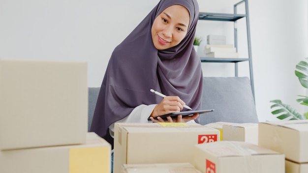 Free photo young muslim businesswoman check product purchase order on stock and save to tablet computer work at home office.