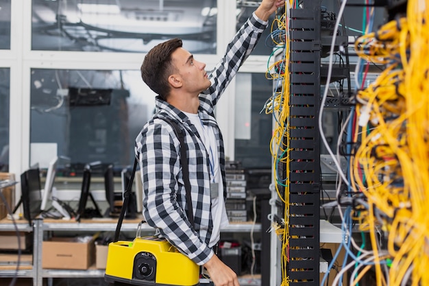 Young network engineer with a box looking at ethernet switches