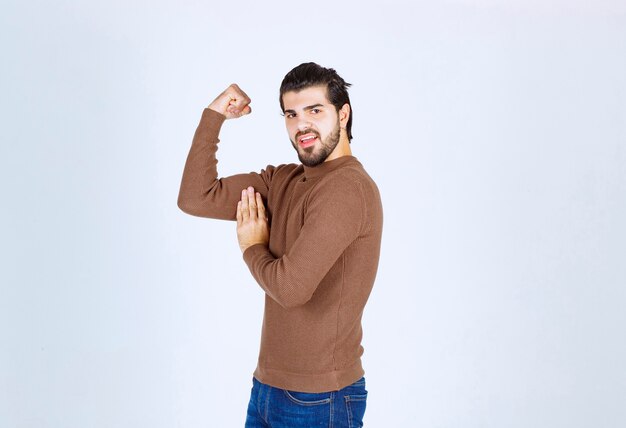 A young nice man model standing and showing his biceps over white wall. High quality photo