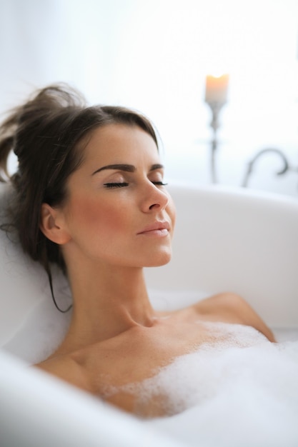 Young nude woman taking a relaxing foamy bath