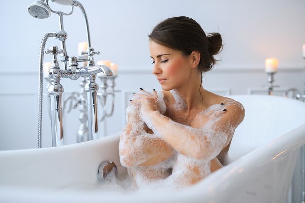 Young nude woman taking a relaxing foamy bath