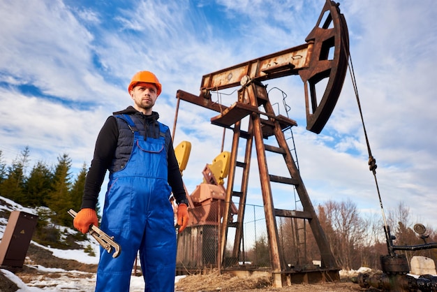 Free Photo young oil man standing in front of pump jack