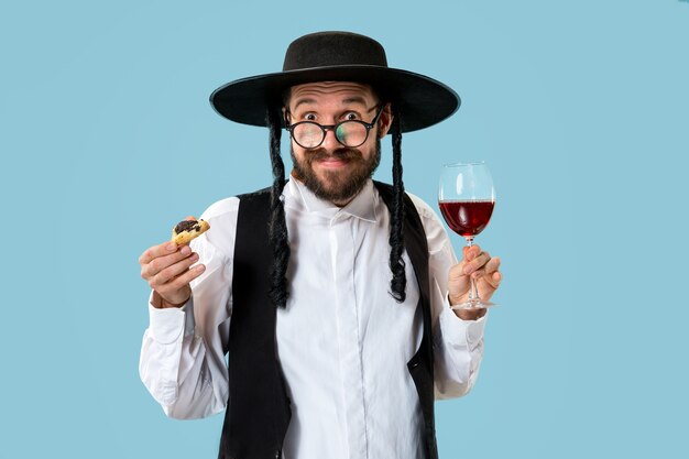 Free photo the young orthodox jewish man with black hat with hamantaschen cookies for jewish festival of purim