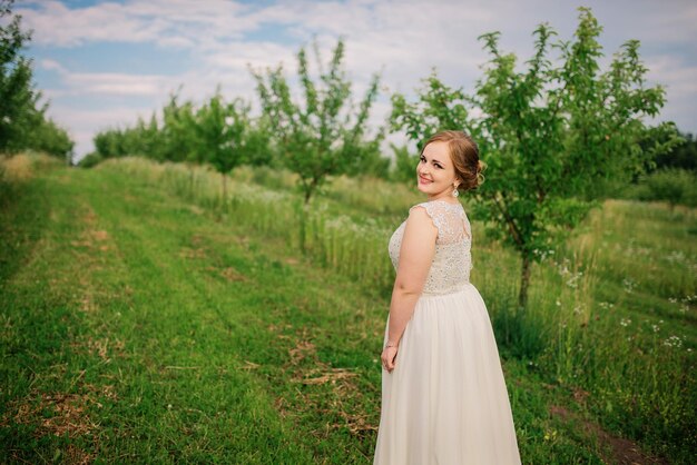 Young overweight girl at beige dress posed background spring garden