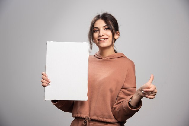 Young painter posing with canvas and giving thumbs up