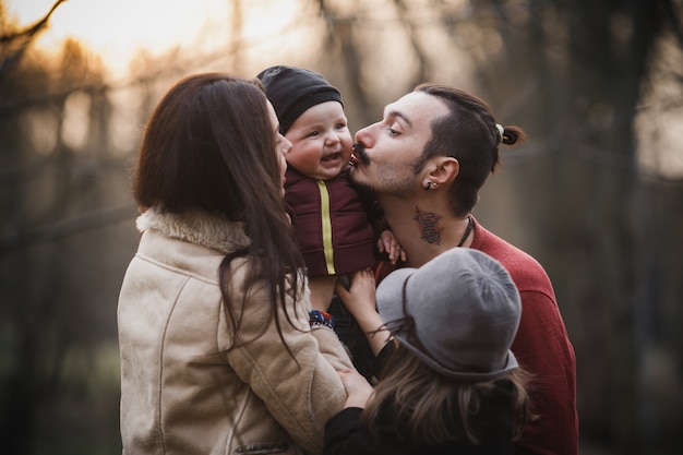 Free photo young parents kissing baby while posing