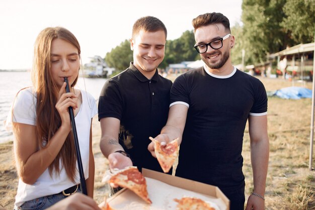 Young people eating pizza and smoking shisha at the beach