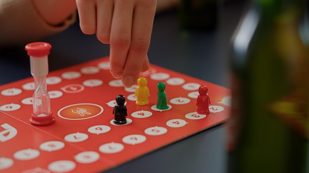 Free photo young people playing charades board games with figurines, rolling dices for cards game. men and women enjoying strategy competition to guess card for entertainment and fun. close up.