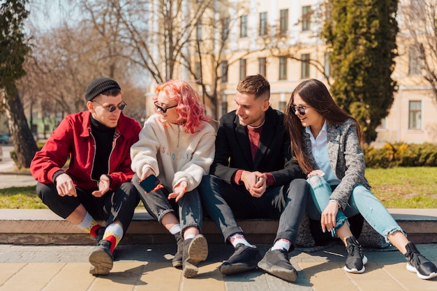 Young people talking while sitting on curb