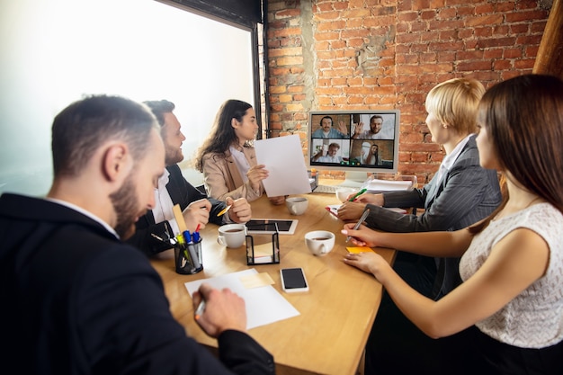 Young people talking, working during videoconference with colleagues at office or living room